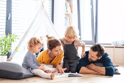 Två föräldrar och två barn sitter i ett barntält inomhus