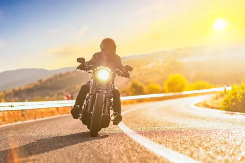 Man kör motorcykel i eftermiddagssol.