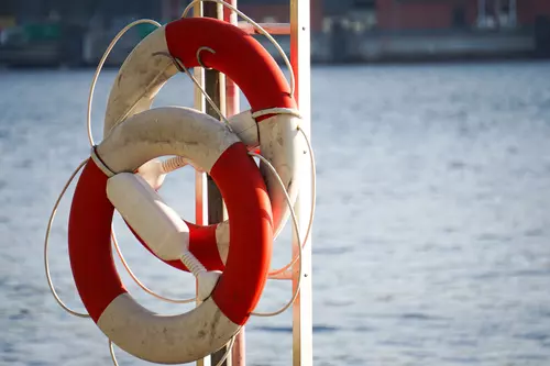 Två livbojar hänger på en stege vid vattnet